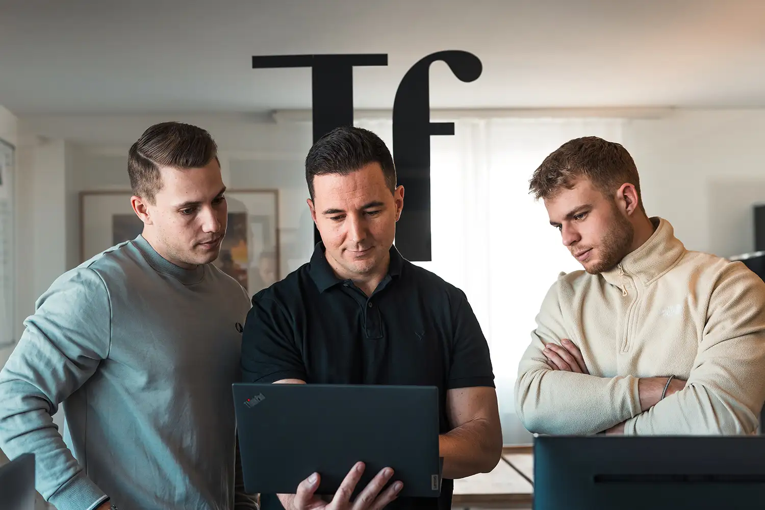 Team Werbeagentur Talfrisch mit Tf Logo im Hintergrund